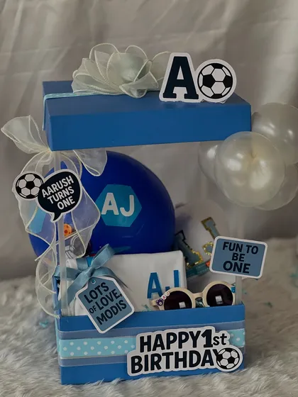 It's a goal! This football-themed first birthday hamper is perfect for a little champ. It includes a personalized t-shirt, a cap, a ball, and other fun accessories.