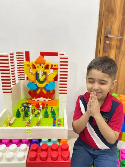 A moment of quiet reverence as a child prays before his completed LEGO Ganesha and pandal setup.