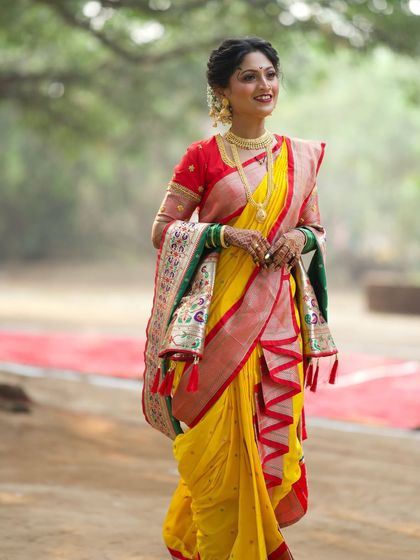 A vibrant yellow and red Nauvari saree, perfect for a traditional outdoor wedding. The draping style is classic, allowing for easy movement while looking absolutely stunning.
