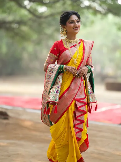 The grace of a bride in a traditional yellow and red Nauvari saree. The draping is done meticulously to create a flattering and authentic look.