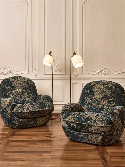 The 'Cluny' tapestry fabric from Nobilis envelops these plush armchairs in timeless elegance. The chenille velvet, featuring a historic Verdure motif, evokes the essence of 17th-century Flanders in two rich, muted colorways.