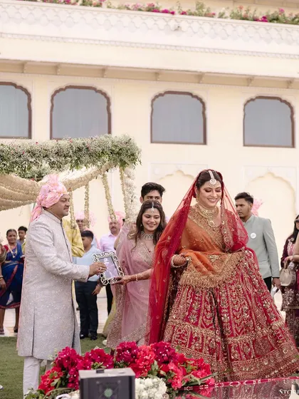 The bride, Shikha, making an emotional entrance with her father, who is holding a portrait of a loved one.