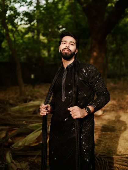 Serving looks hotter than a Delhi summer. A model looks effortlessly cool in a black sequined kurta set, shot in a natural, outdoor setting.