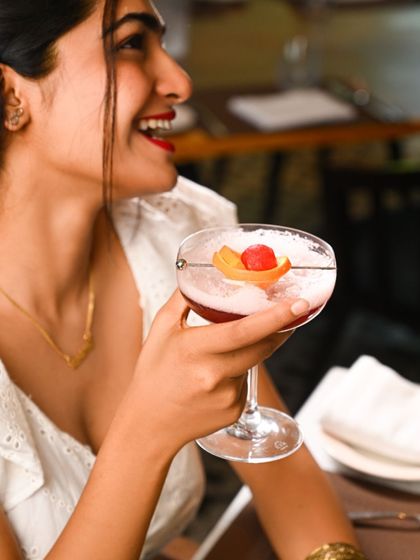 Set the mood for Valentine's Day with a romantic dining experience. A guest smiles while holding a beautifully garnished cocktail, ready for an evening of love and luxury.
