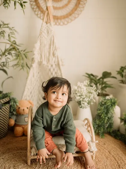 A sweet, contemplative look from this little one, sitting on a miniature bed prop.