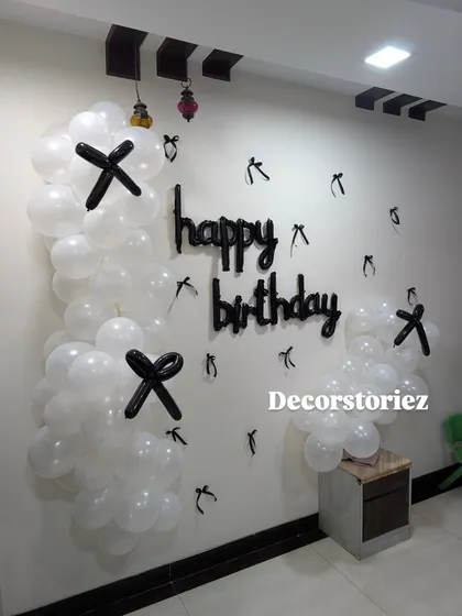 For a minimalist and modern look, I can create simple wall decorations like this one using white balloons with black balloon accents and a 'happy birthday' cutout.