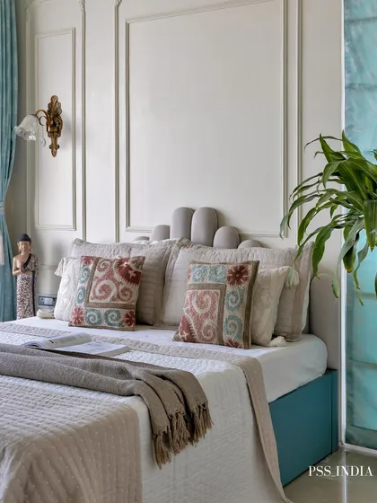 Classic elegance defines this bedroom. Intricate wall moldings provide a timeless backdrop, while the soft, tufted headboard and layers of plush bedding in pastel tones create a space that feels both grand and incredibly comfortable.