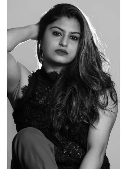 A close-up black and white portrait with a strong, direct gaze. The lighting sculpts her features and adds a sense of drama.