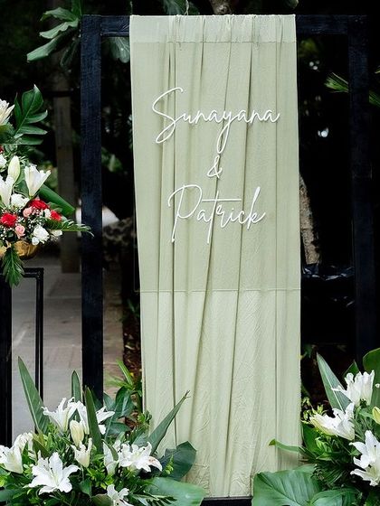 A modern welcome sign with elegant draping and floral arrangements for a cross-cultural wedding.