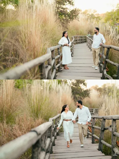 A happy couple walks along a rustic wooden bridge surrounded by tall, dry grass, capturing a natural and joyful moment in Jaipur.