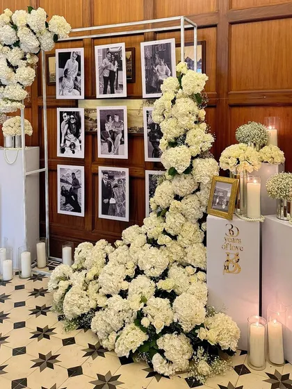 An elegant 30th-anniversary celebration featuring a photo wall of the couple's memories, framed by a cascade of white hydrangeas.