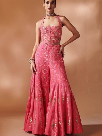 Blush bloom perfection. This pink halter-neck jumpsuit or sharara set features hand-embroidered floral details, perfect for a garden wedding or a dreamy day event.