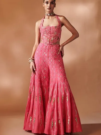 Blush bloom perfection. This pink halter-neck jumpsuit or sharara set features hand-embroidered floral details, perfect for a garden wedding or a dreamy day event.