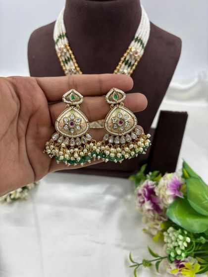 Our "Indira" premium antique gold necklace set. This long necklace features a large, intricately designed pendant with Meenakari work and comes with matching statement earrings.