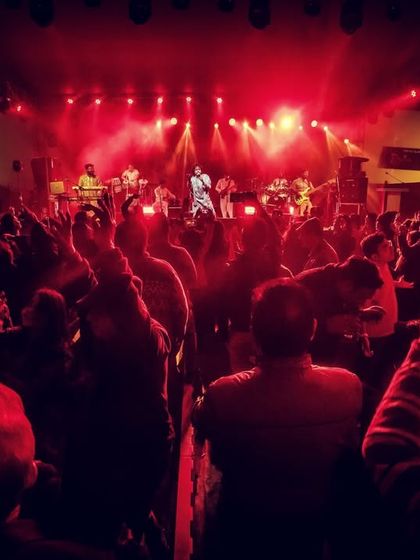 A wide shot of the packed venue at DKS Club. The red lights reflect the fiery passion and energy of the night.