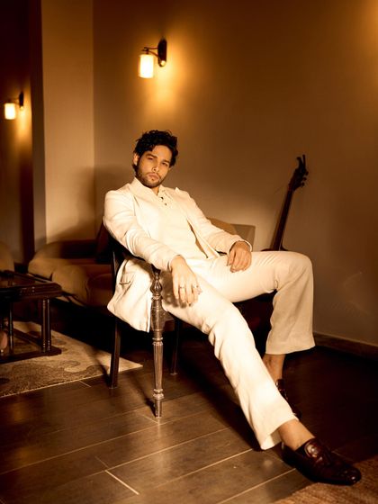 A different perspective of the all-white suit look for Grazia. The warm, ambient lighting complements the ivory tone of the suit, creating a sophisticated and moody atmosphere.