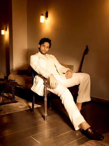 A different perspective of the all-white suit look for Grazia. The warm, ambient lighting complements the ivory tone of the suit, creating a sophisticated and moody atmosphere.