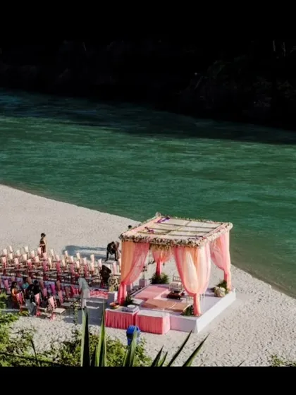 A beautiful shot of a wedding mandap set up on the sandy banks of the Ganga river in Rishikesh, ready for a serene destination wedding ceremony.