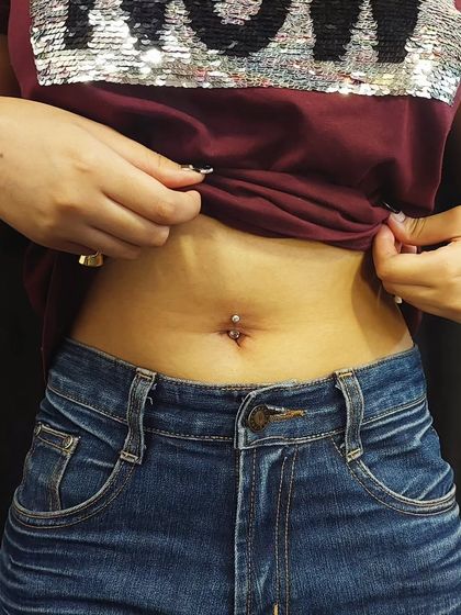 A freshly done navel piercing with a standard silver-tone barbell. I provide detailed piercing aftercare tips to help with the healing process.