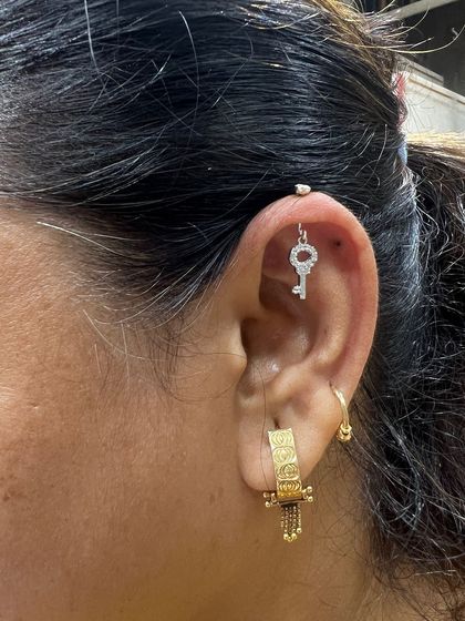 This look is all about unique charms. A key-shaped hanging in the helix is paired with a textured gold hoop, creating a story of its own.