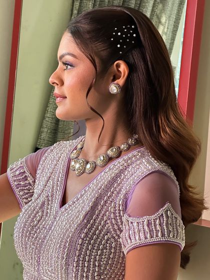 A side profile of a soft, wavy hairstyle pinned back with a sparkling barrette. This is a simple yet sophisticated look, ideal for a guest at a wedding or a pre-wedding event.