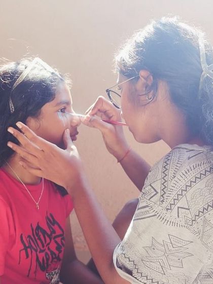 A moment of concentration as one camper carefully applies face paint to her friend.