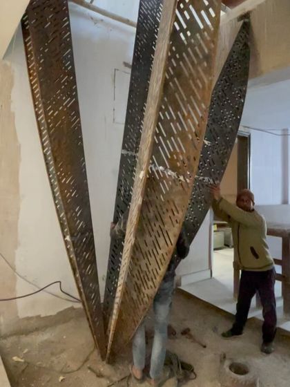 On-site installation of a large, perforated metal staircase. This photo captures the hands-on, collaborative effort required to bring complex, innovative design elements to life.