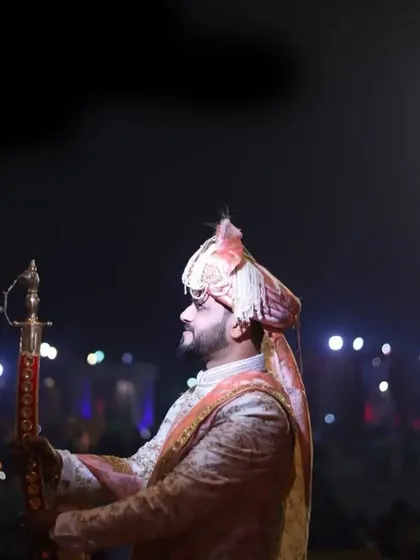 A powerful shot of the groom making his entrance at the wedding venue, illuminated by stage lights for a cinematic effect.