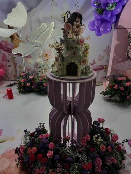 The incredible enchanted garden birthday cake, designed to look like a fairy house and surrounded by floral arrangements.