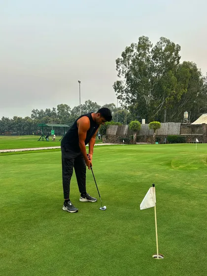 A golfer in all black lines up a crucial putt on the practice green.