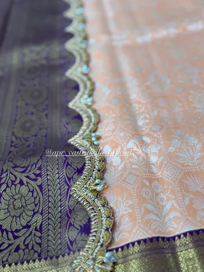 A scalloped border with delicate white floral embroidery, contrasting beautifully with the purple and gold woven silk.