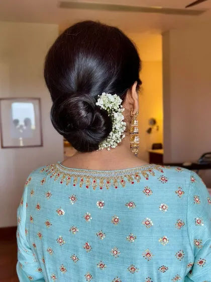 The elegance is in the details. A classic, neat bun adorned with fresh flowers perfectly complements her serene and simple makeup look for the Anand Karaj ceremony.