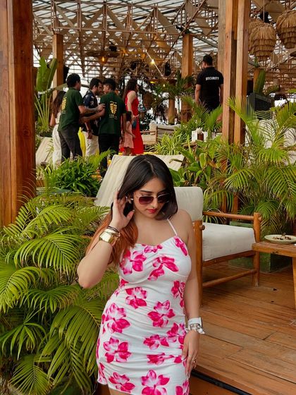 A confident pose in the floral dress. The lush green background of the cafe makes the pink flowers on the dress pop.