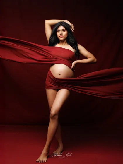 A full-body shot showcasing a dramatic pose with flowing red fabric, creating a powerful and artistic fine-art maternity photograph.