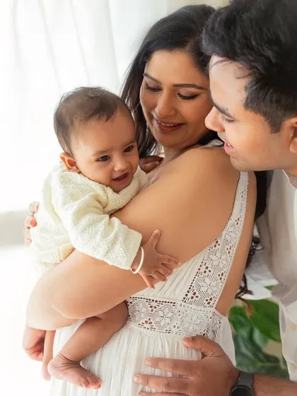 A candid moment of love and laughter. The genuine interaction between the parents and their baby is what makes this 6-month milestone photo so precious.