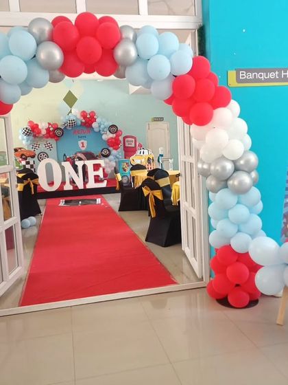A red, white, and silver balloon arch creating an exciting entrance for a 'Cars' themed first birthday.