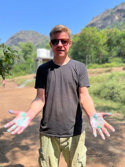 A participant showing off his paint-covered hands at an outdoor festival. These events are all about letting loose and having fun with art.