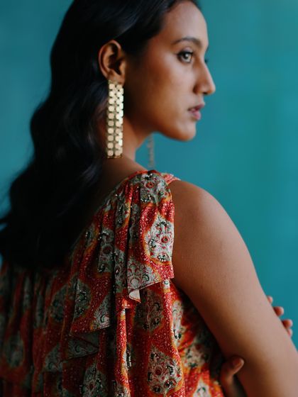A profile shot from the same series, highlighting the model's wavy hair, statement earrings, and the print detail on the shoulder.