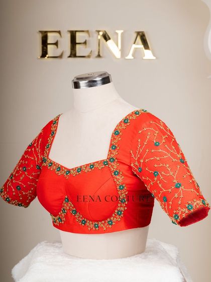 A simple yet striking design. This bright red raw silk blouse features a delicate creeper embroidery pattern in gold and teal thread, with a classic square back and matching handmade tassels.