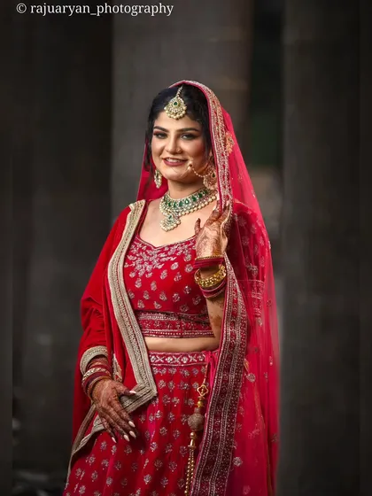 A classic bridal portrait showcasing the elegance of the bride. Her smile and pose radiate happiness and confidence in her beautiful red wedding lehenga.