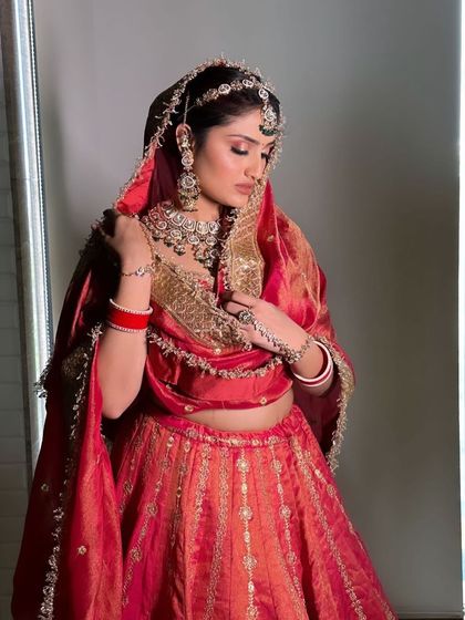 A series of a bride in a traditional red and gold silk lehenga. The poses and styling are perfect for creating a classic, timeless bridal album.