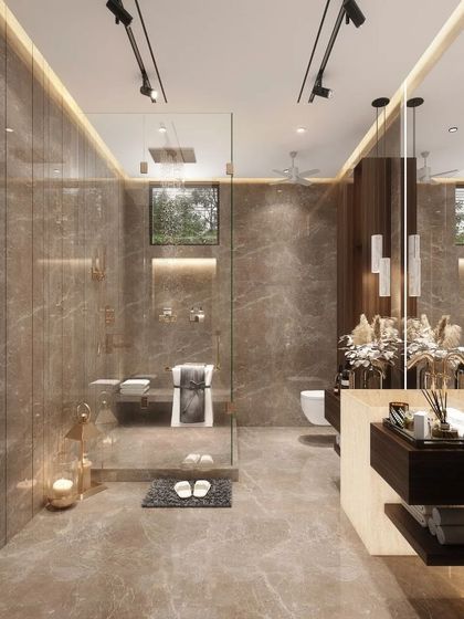 This spacious bathroom and dressing area is wrapped in warm, brown-toned marble. The design includes a large walk-in shower with a glass partition and integrated shelving, creating a seamless and luxurious personal grooming space.