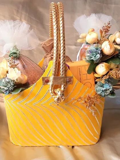 This vibrant yellow fabric basket is a perfect solution for all your festive gifting needs. It's filled with treats and decorated with floral accents, suitable for Diwali, Ganpati, and other celebrations.