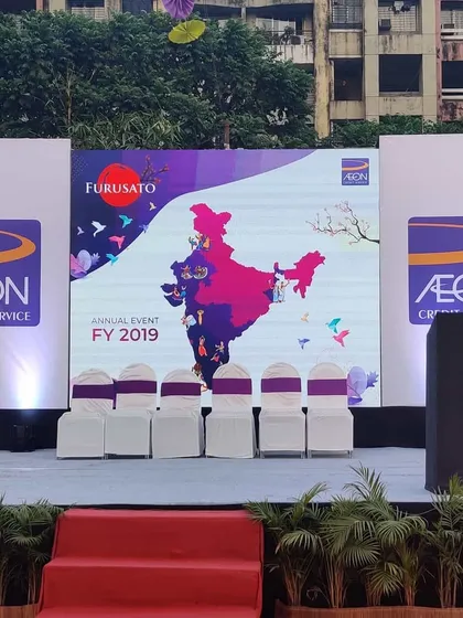 A clear view of a stage I designed for the AON Credit Service annual event. The setup features a large, high-resolution LED screen for presentations, flanked by branded panels, demonstrating how I integrate corporate identity directly into the main focal point of an event.