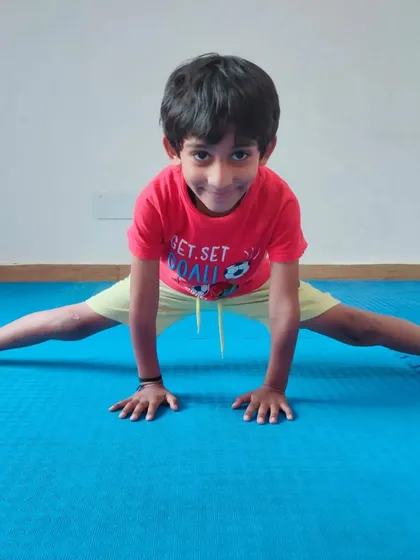 A young student smiles while performing a split stretch. We believe in making fitness and discipline an enjoyable journey for our kids.