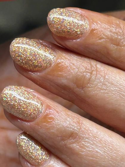 A warm, sparkling gold glitter manicure. This festive look is perfect for celebrations and adds a touch of luxury.