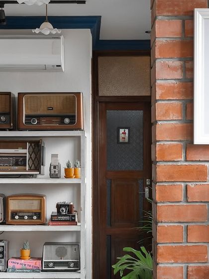 A shelf of vintage radios and cameras at Klaa Kitchen adds a personal and nostalgic touch. These curated objects, set against an exposed brick wall, help build the story of a space filled with memories and history.