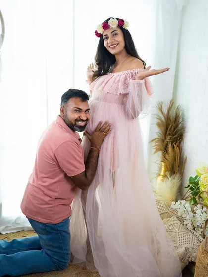 A fun and playful moment between partners. The dad-to-be listens to the baby bump while the mom-to-be gestures with a smile, capturing the joy of their journey.