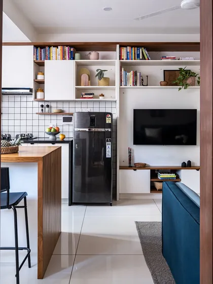 In the 'Footloose' studio apartment, the kitchen cabinetry extends into a full entertainment and library unit, creating a seamless, unified look for the open-plan space.