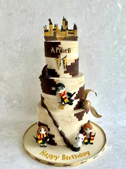 Bringing the magic of Hogwarts to life for an 11th birthday. This three-tiered Harry Potter cake features the iconic brick pattern, a golden snitch, and fondant figurines of Harry, Ron, and Hermione.